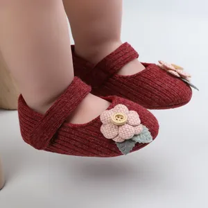 Nahaufnahme der weichen Strickstruktur und der Zierblume auf roten Babyschuhen