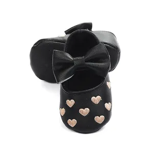 Detailansicht schwarzer Baby-Prinzessinenschuhe mit Herzstickerei und großer Schleife.