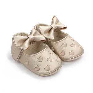 Detail von goldenen Baby-Prinzessin-Laufschuhen mit Schleife und Herzmuster