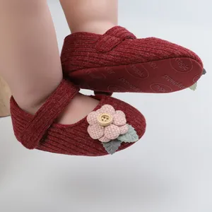 Detailaufnahme roter Strick-Babyschuhe für Mädchen mit Blumenverzierung und Rutschsohle