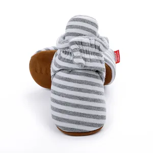 Vue détaillée de chaussons rayés gris et blanc pour bébé avec semelles marron.