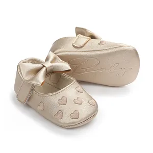 Detailansicht der goldenen Baby-Prinzessinenschuhe mit Schleife und Herzstickerei