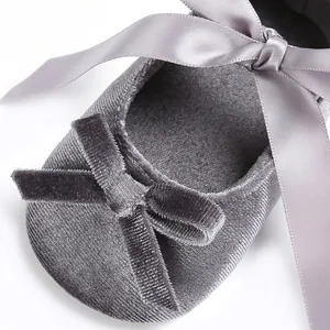 Gros plan sur une chaussure de bébé en velours gris avec un nœud en ruban de soie