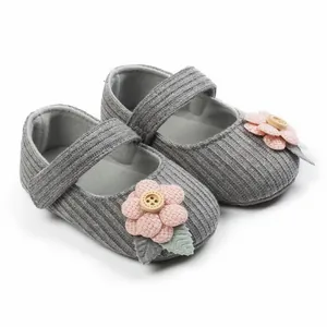 Nahaufnahme grauer Baby-Strickschuhe für Mädchen mit rosa Blume und Holzknopf-Details