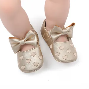 Nahaufnahme goldener Baby Prinzessin Laufschuhe mit großer Schleife und Herzmustern