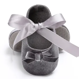 Gros plan sur la texture en velours gris et le nœud élégant en satin des chaussures bébé