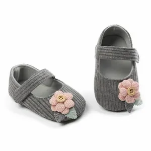 Nahaufnahme grauer Babyschuhe für Mädchen mit rosa Blume und dekorativem Holzknopf