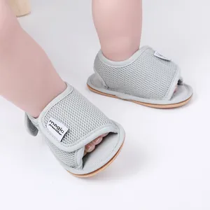 Detaillierte Nahaufnahme von grauen, atmungsaktiven Mesh-Babysandalen mit Klettverschluss.