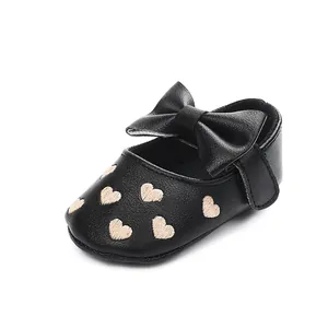 Detailansicht eines schwarzen Baby-Prinzessin-Schuhs mit Schleife und Herzmustern