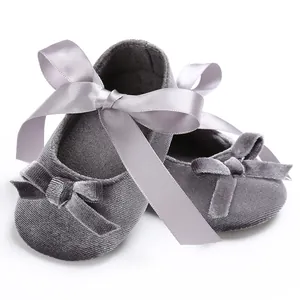 Vue détaillée de chaussures bébé en velours gris avec grand nœud en satin argenté.