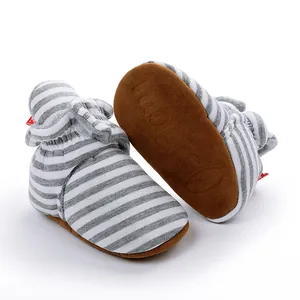 Détail de bottes rayées gris et blanc pour bébé avec doublure en peluche et semelles brunes