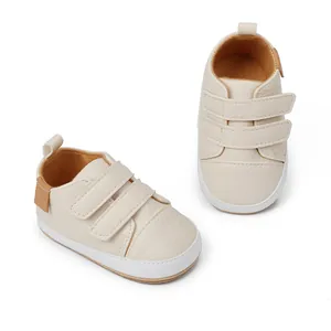 Close-up view of cream infant walking shoes featuring dual adjustable velcro straps.
