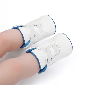 Close-up of white baby basketball shoes with blue trim on an infant's feet