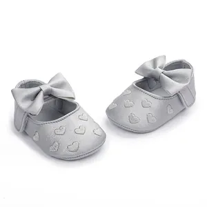 Detailansicht silberner Baby-Prinzessinenschuhe mit Herzstickerei und Schleife