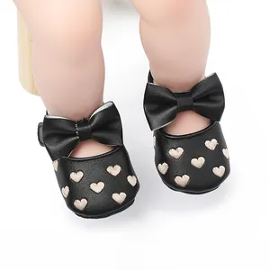 Nahaufnahme schwarzer Baby-Prinzessin-Schuhe mit gestickten Herzen und Schleife