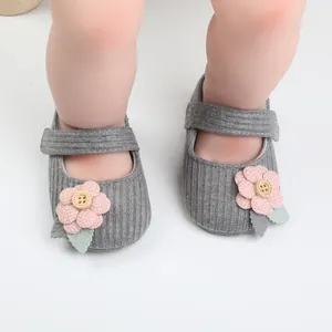 Nahaufnahme von gestrickten Babyschuhen für Mädchen mit rosa Blume und Holzknopf