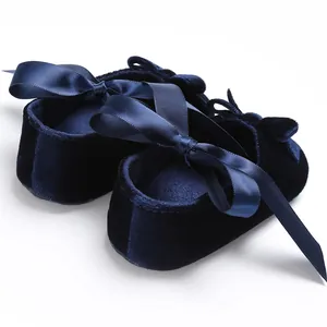 Gros plan sur des chaussures de marche en velours bleu marine pour bébé avec nœud en satin