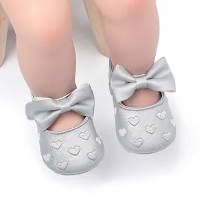 Detailansicht silberner Baby-Prinzessin-Schuhe mit großer Schleife und Herzstickerei
