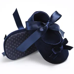 Gros plan de chaussures bébé en velours bleu marine avec un nœud en ruban satiné