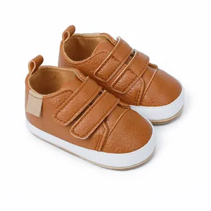 Close-up view of brown faux leather baby sneakers with double Velcro straps and white sole