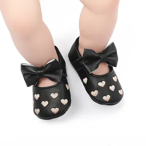 Detailansicht schwarzer Baby-Prinzessinenschuhe mit Herzstickerei und Lederschleife.