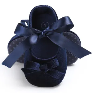 Détail de chaussures pour bébé en velours bleu marine avec semelles souples et rubans