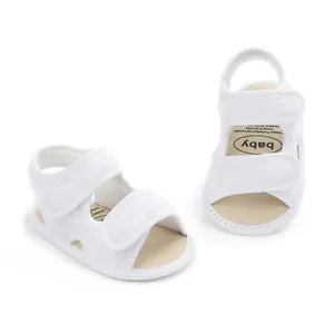 Detailweergave van ademende witte babyloopsandalen met een dubbele klittenbandsluiting.
