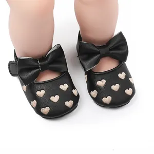 Detailansicht von schwarzen Baby-Prinzessinnen-Schuhen mit dekorativer Schleife und Herzstickerei.