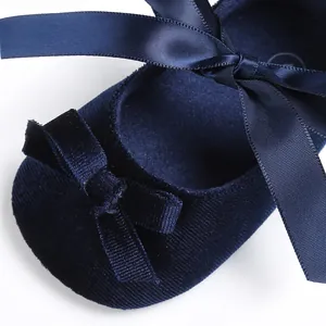 Détail de chaussure de marche bébé en velours bleu marine avec un nœud en ruban satin