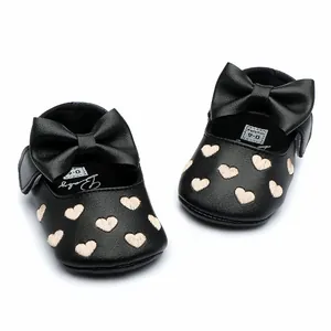 Close-up of black baby girl walker shoes with embroidered hearts and a large bow
