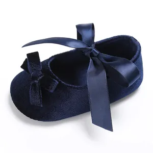 Gros plan de chaussure bébé en velours bleu marine avec un élégant nœud en satin.
