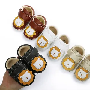 Vue détaillée des chaussures pour bébés avec lion de dessin animé en marron, blanc et or.