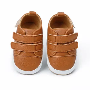 Close-up view of brown baby first walker shoes with dual velcro straps and white soles.
