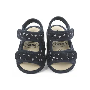 Close-up of navy blue baby sandals with white triangle patterns and velcro straps.