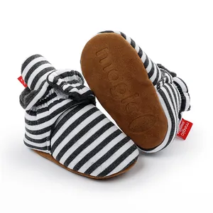 Gros plan de bottes d'hiver pour bébé à rayures, doublure polaire et semelle marron souple.