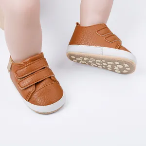 Close-up detail of brown faux leather baby walking shoes with white non-slip soles
