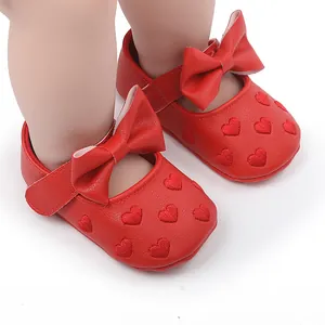 Detailaufnahme roter Baby-Prinzessinenschuhe mit Herzstickerei und einer großen Schleife.