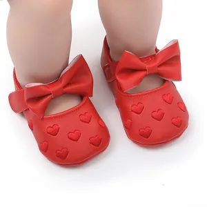 Nahaufnahme von roten Lauflernschuhen für Babys mit Herzstickerei und Schleifen.
