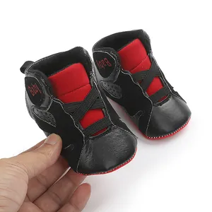 Detailed macro view of black and red soft-sole baby sneakers for infants and toddlers.