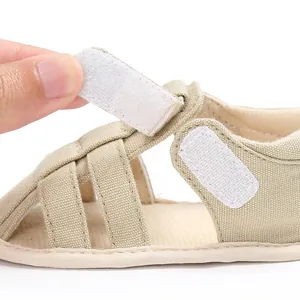 Macro view of the adjustable hook and loop fastener on these beige baby boy sandals