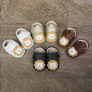 Primer plano de zapatos de gateo para bebé con leones sobre fondo de madera