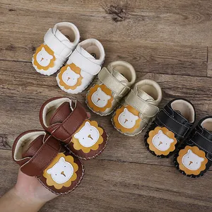 Vista detallada de zapatos de bebé con diseño de león en varios colores sobre suelo de madera