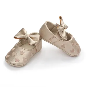 Detailansicht goldener Baby-Prinzessinenschuhe mit Herzstickerei und schöner Schleife
