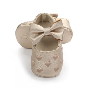 Detailansicht goldener Lauflernschuhe für Babys mit Herzstickerei und großer Schleife