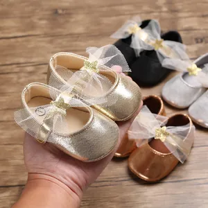 Nahaufnahme von goldenen Baby-Prinzessin-Schuhen mit Netzschleife und Glitzerstern.