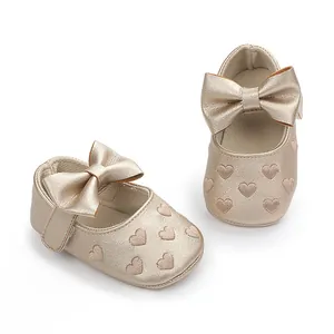 Detailansicht goldene Baby-Prinzessinenschuhe mit Herzmuster und großer Schleife