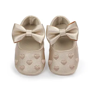 Nahaufnahme goldener Prinzessinnenschuhe für Babys mit Schleifen und Herzstickerei