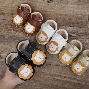 Vista de detalle de los zapatos de bebé con diseño de león en varios colores vivos.