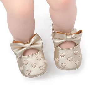 Detailansicht der champagnergoldenen Babyprinzessinnenschuhe mit Herzstickerei und Schleife