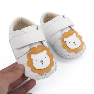 Gros plan de chaussures blanches pour bébé avec une tête de lion orange.